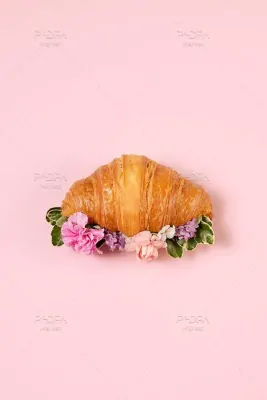عکس استوک کروسان تزئین شده با گل های سفید و صورتی