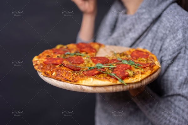 عکس با کیفیت پیتزا پپرونی در دست زن