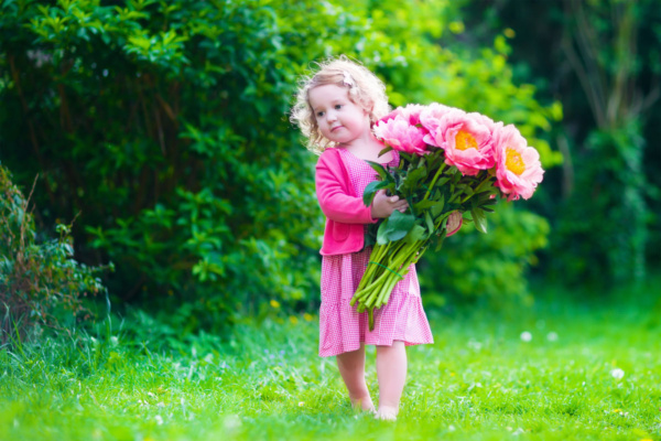 عکس استوک دختر بچه با دسته گل داخل باغ