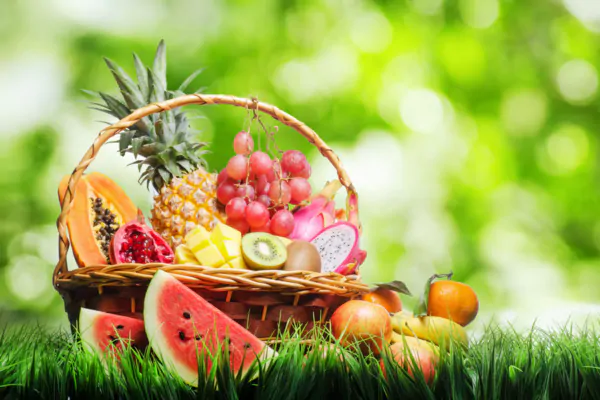 عکس استوک میوه داخل سبد حصیری روی چمن در طبیعت