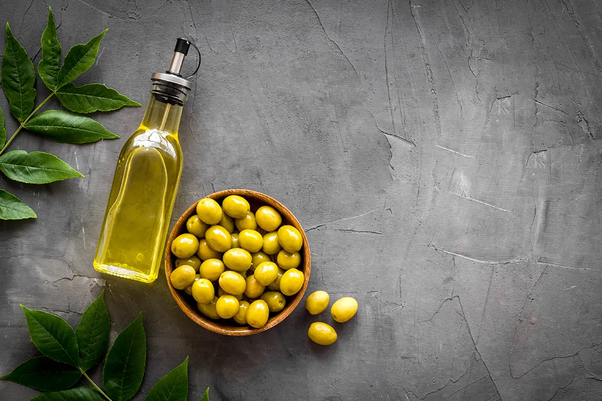 زیتون سبز و روغن زیتون روی سطح سنگی